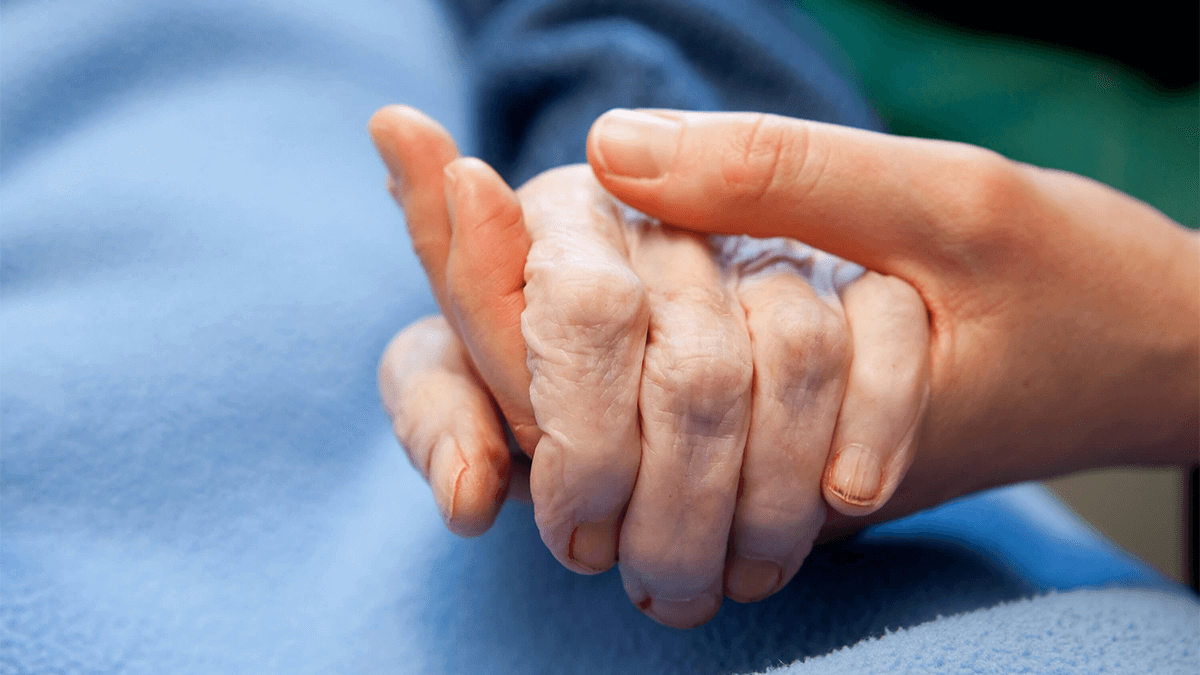 A carer holding an elderly client's hands